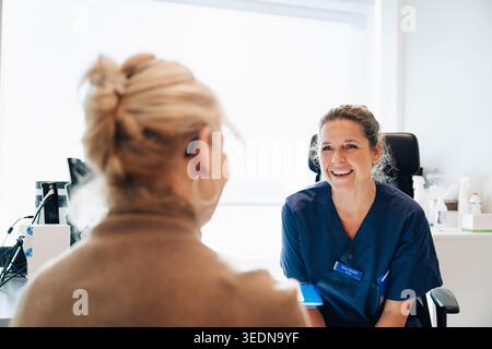 Glückliche Ärztin im Gespräch mit Seniorpatienten in der medizinischen Klinik Stockfoto