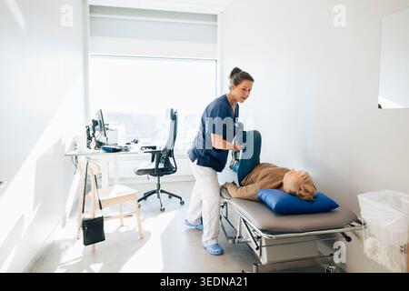 Physiotherapeutin Streckbein einer älteren Frau, die im Krankenhaus auf dem Untersuchungstisch liegt Stockfoto
