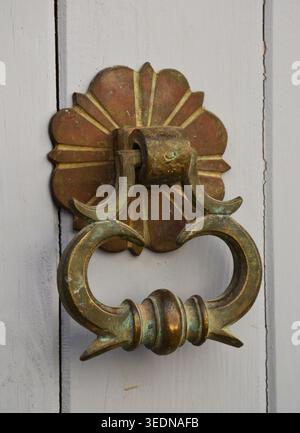 Antik verzierte Messingtür an einer grau lackierten Holztür Stockfoto