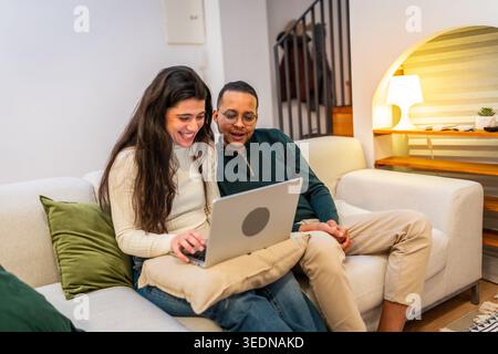 Glückliches Paar, das sich auf dem Sofa mit einem Laptop entspannt Stockfoto