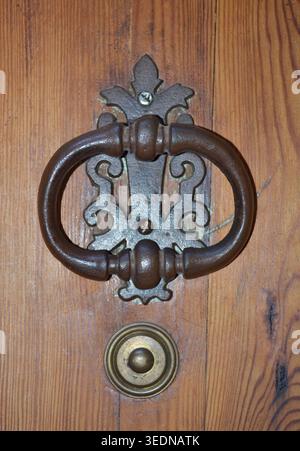 Antike Eisentürklopfer an einer rustikalen Holztür Stockfoto
