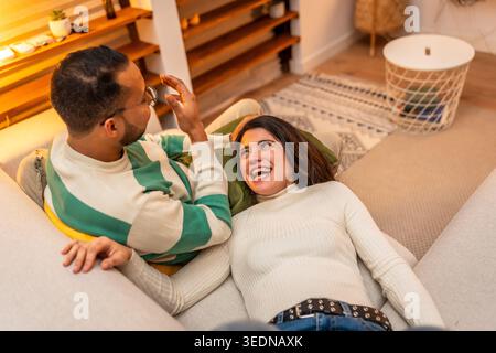 Glückliches junges Paar, das sich zu Hause auf dem Sofa entspannt Stockfoto