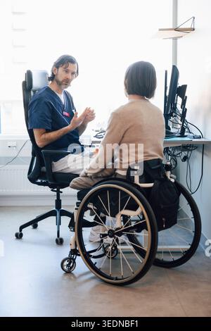 Männlicher medizinischer Experte im Gespräch mit körperlich behinderter Patientin im Krankenhaus Stockfoto