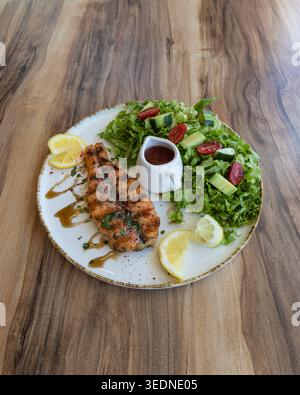 Gegrilltes Lachsfilet mit frischem grünem Salat und Zitrone auf Holztisch Stockfoto