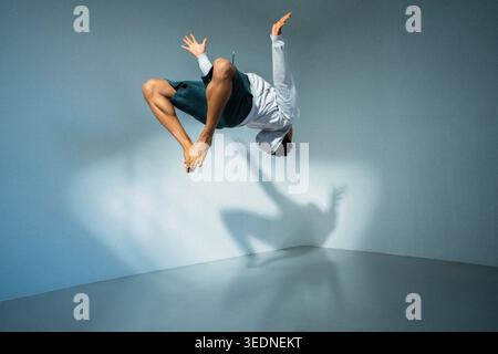 Blick auf die gesamte Länge des jungen Mannes, der Backflip vor der Wand durchführt Stockfoto
