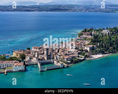Blick aus der Vogelperspektive auf die Burg Scaligero und die historische Halbinsel Sirmione, umgeben vom türkisfarbenen Wasser des Gardasees Sirmione, Lombardei, Italien. Stockfoto