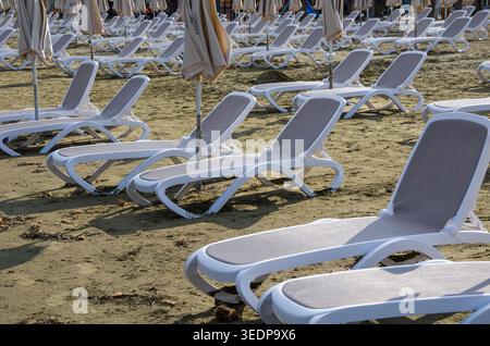 Leere Strandliegen mit Sonnenschirmen Stockfoto