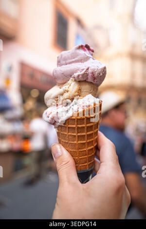 Hand mit einer Eiscreme aus drei Schaufeln während eines Sommerurlaubs in Rom, Italien Stockfoto