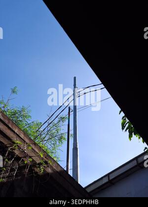 Hoch aufragende Elektromaste vor einem Hintergrund des klaren blauen Himmels Stockfoto