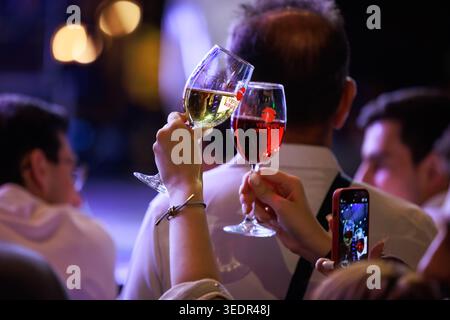 Bei den Weintagen in Jerewan versammeln sich Menschen, die Weingläser halten, während ein Besucher den Moment während des Festivals mit einem Smartphone festhält. Stockfoto