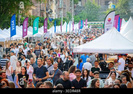 Bei den Yerevan Wine Days Festival füllen die Besucher während der Veranstaltung in Jerewan eine überfüllte Festivalstraße, gesäumt von weißen Verkostungszelten und Sponsorenflaggen. Stockfoto