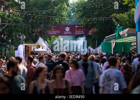 Beim Yerevan Wine Days Festival spazieren die Besucher während des Festivals entlang einer überfüllten Festivalstraße, gesäumt von Verkostungszelten unter dem Festivalbanner. Stockfoto