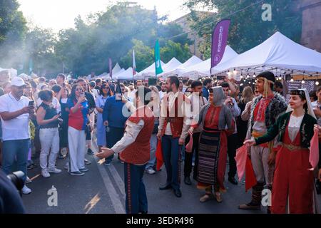 Während des Festivals in Jerewan werden die Festivalbesucher in traditionellen armenischen Kostümen auf einer überfüllten Straße unterhalten. Stockfoto