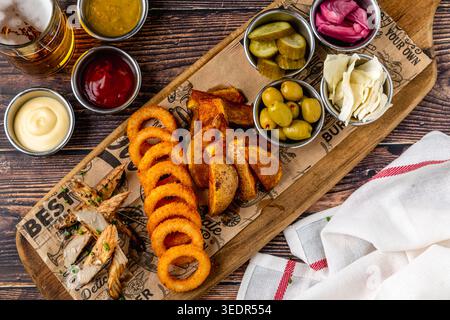 Knusprige gebratene Snacks auf Platte mit Saucen und Bier auf rustikalem Tisch Stockfoto