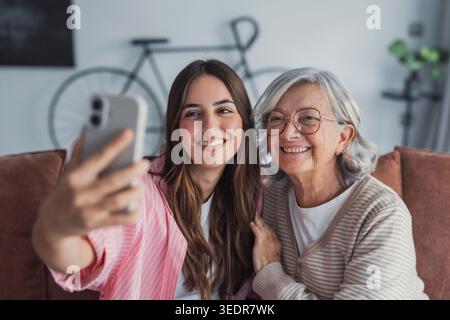 Kopfaufnahme Porträt Glückliche Frau mit reifer Mutter, die zusammen Selfie auf dem Smartphone macht, Kamera ansieht, lächelnde ältere Mutter und aufgeregte Erwachsene Tochter, die Spaß mit der Kamera hat, Videos aufnimmt Stockfoto