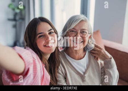 Kopfaufnahme Porträt Glückliche Frau mit reifer Mutter, die zusammen Selfie auf dem Smartphone macht, Kamera ansieht, lächelnde ältere Mutter und aufgeregte Erwachsene Tochter, die Spaß mit der Kamera hat, Videos aufnimmt Stockfoto