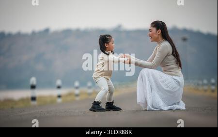 Glückliche Mutter und Kind, die Hände auf einer Straße in der Nähe des Sees halten Stockfoto