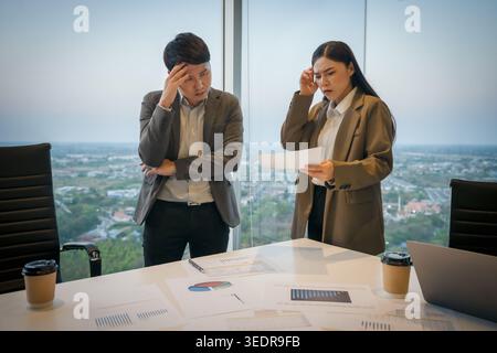 Betonte zwei Geschäftskollegen, die sich in modernen Büros treffen und ernsthafte Argumente oder Meinungsverschiedenheiten über Papierkram hatten Stockfoto