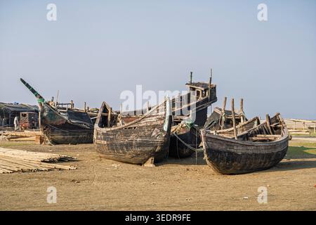 Malerischer Blick auf heruntergekommene Holzfischboote am Dorfstrand Nazirartek, Cox's Bazar, Bangladesch Stockfoto