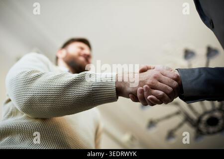 Junge Männer schütteln sich die Hände während des Treffens, signalisieren Vereinbarung, Partnerschaft, Vertrauen, Geschäft. Flache Ansicht, nützlich für Unternehmensverhandlungen, Personalbeschaffung und Vertrieb Stockfoto