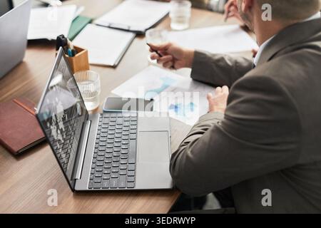 Geschäftsleute diskutieren die Strategie während der Besprechung im Büro, indem sie Laptop und Dokumente verwenden. Ideal für Unternehmensplanung, Teamarbeit, Finanzen, Analysen Stockfoto