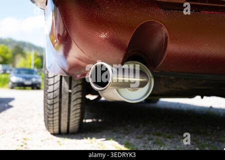 Eine Nahaufnahme einer einzelnen kreisförmigen Abgasspitze an einem braunen Auto. Das gebürstete Metallrohr wird von hinten gezeigt und hebt den Schalldämpfer hervor Stockfoto