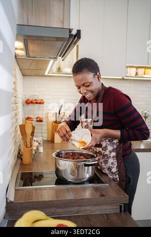 Glückliche afroamerikanische Frau, die in der Küche kocht Stockfoto
