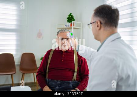 Der Arzt misst die Temperatur eines älteren Patienten in einer hellen Klinik. Stockfoto