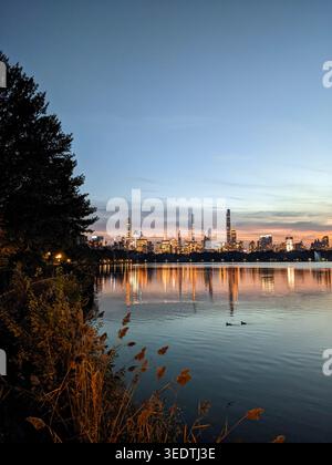 Sonnenuntergang über einem Central Park Lake mit der Silhouette der Manhattan Skyline im Hintergrund Stockfoto