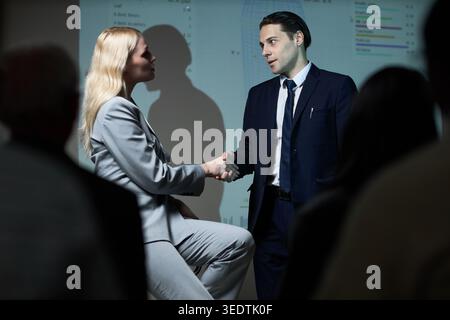 Geschäftsmann und Geschäftsfrau schütteln während der Präsentation die Hand Stockfoto