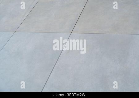 Nahaufnahme moderner grauer Fliesen, die ein klares geometrisches Muster bilden. Idealer Hintergrund für Architektur und Designkonzepte. Stockfoto