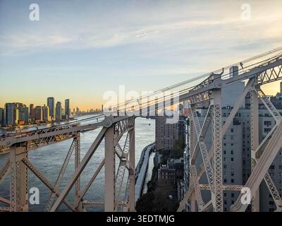 Kabelleitungen, Türme voraus – Manhattan erhebt sich jenseits des Gehwegs der Brooklyn Bridge in der Dämmerung Stockfoto