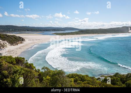 Panoramablick auf eine unberührte Küstenbucht, wo das türkisfarbene Meer auf einen Flusseingang trifft, mit weißem Sandstrand und üppigem grünem, einheimischem Buschland Stockfoto