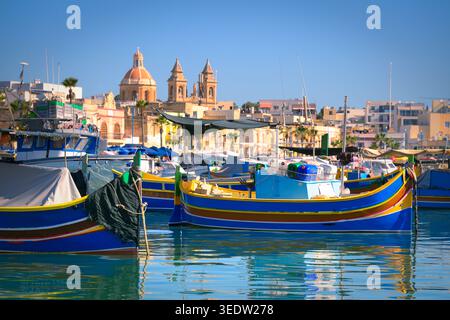 Blaue Luzzu-Boote im Hafen des mediterranen Fischerdorfes an einem Sommermorgen, Marsaxlokk, Malta. Stockfoto