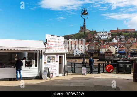 Die Hafenfront-Szene in Whitby, North Yorkshire, bietet einen kleinen Imbisskiosk, in dem traditionelle Fish and Chips, Tee, Kaffee und kalte Getränke angeboten werden. Stockfoto