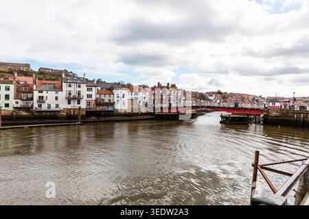 Blick auf den Fluss in Whitby, North Yorkshire, mit der roten Hängebrücke, die den Esk überspannt und beide Seiten der Stadt verbindet. Schwinge Stockfoto