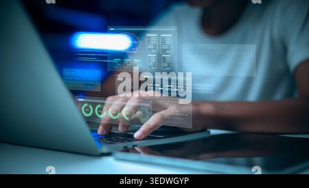 Programmierer-Codierung auf Laptop mit HUD-Symbolen auf virtuellem Bildschirm. Software-Ingenieur entwickelt KI-Gehirntechnologie und Big-Data-Analyse im dunklen Büro Stockfoto