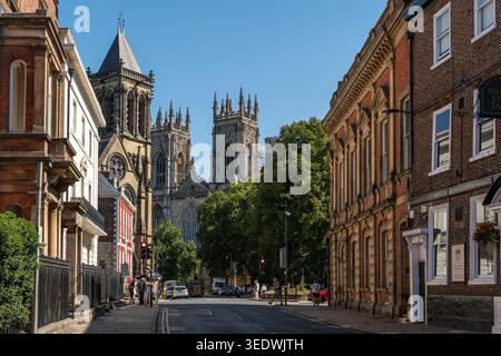 Eine Straße in York, die an einem sonnigen Sommertag in England zu den Türmen des York Minster führt Stockfoto