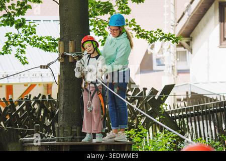 Ein aktives Hobby in der Natur. Ein glückliches Kind, das an einem Sommertag eine Aktivität in einem Hochseilgarten genießt. Stockfoto