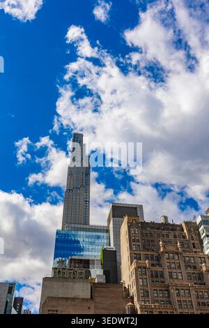 Hohe Gebäude dominieren die Skyline, während sich Wolken über die Skyline ziehen und die städtische Schönheit von New York City bezeugen. Die Sonne scheint hell und verleiht ihr Lebendigkeit. Stockfoto