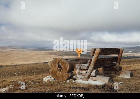 Rustikale Holzbank und Tisch auf offenem Bergrasenland unter massiven Sturmwolken. Stockfoto