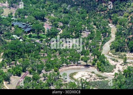 Blick auf ein lebhaftes grünes Tal mit einem sich schlängelnden Fluss und verstreuten Gebäuden. Ruhig, landschaftlich reizvoll. Für Reisen, Natur, Umwelt Stockfoto