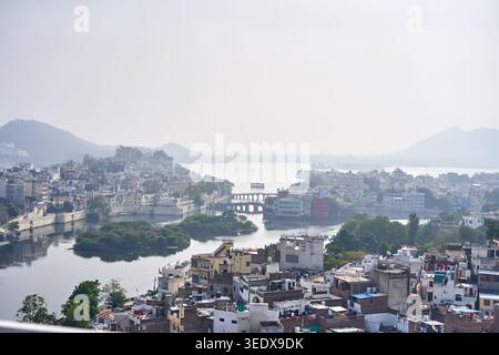 Eine panoramische Luftaufnahme der Stadtlandschaft von Udaipur in Rajasthan, Indien, mit dem Pichola-See und seinen üppigen grünen Inseln sowie dem historischen Ufergefüge Stockfoto