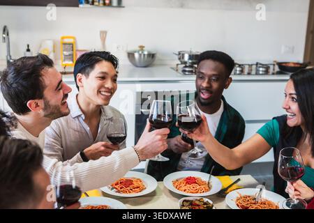 Vielfältige Gruppe junger Menschen, die gemeinsam essen und feiern Stockfoto