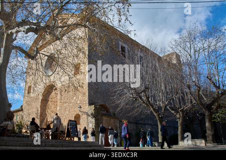 Valldemossa, Spanien - 6. Mai 2026: Die Menschen entspannen sich in einem Café im Freien vor der historischen Steinfassade des Charterhauses von Valldemossa unter A Stockfoto
