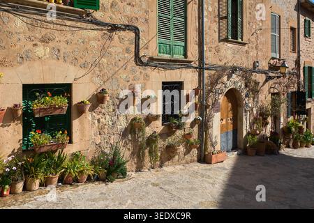 Valldemossa, Spanien - 6. Mai 2026: Malerischer Blick auf die Straße auf traditionelle Steinhäuser mit grünen Fensterläden und zahlreichen bunten Blumentöpfen, die an der hängen Stockfoto