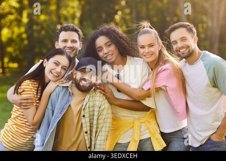 Freunde, die im Freien glücklich sind, eine Gruppe junger Erwachsener, die eng zusammenstehen und einander umarmen Stockfoto