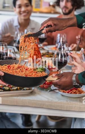 Verschiedene Freunde genießen ein Spaghetti-Abendessen, servieren und essen köstliche italienische Gerichte Stockfoto