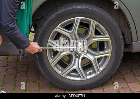 Zum Wechseln eines Autoreifens müssen Sie die Schrauben am Rad lösen, um den Reifen zu entfernen. Die Position, in der der Schraubenschlüssel gehalten wird, bestimmt die Hebelwirkung Stockfoto