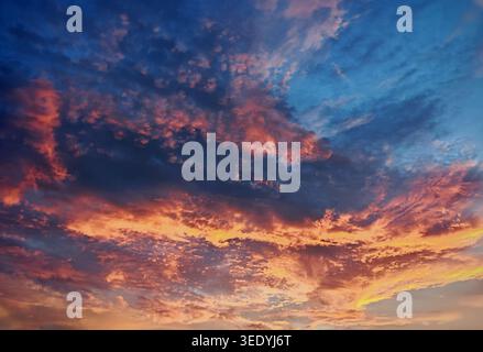 Warme orange und rosafarbene Wolken leuchten während der goldenen Stunde oder in der Dämmerung in einem satten blauen Himmel Stockfoto